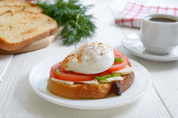 Sandwich with whole grain bread, goat cheese, fresh tomatoes and poached egg. Healthy breakfast.