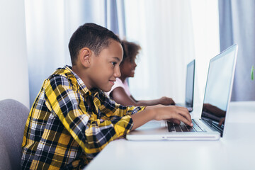 African American elementary students using computer and following classes online due to coronavirus pandemic.