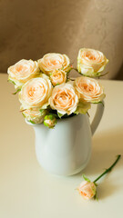Bouquet of delicate tea roses in a white milk jug