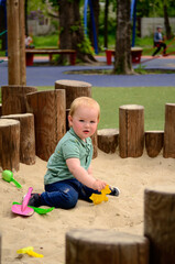 a little boy playing in a sandbox made of wooden beams