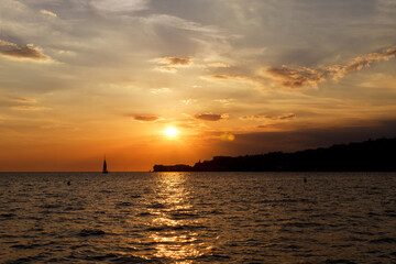 Picturesque seaside resort town in Slovenian coast against orange sunset sky in summer. Scenic view to Adriatic sea in the evening. Travel concept. 