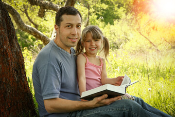 young father with a small daughter reading the Bible
