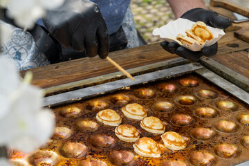 man serving the Dutch specialty Poffertjes from an outdoor griddle