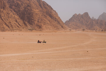Fototapeta na wymiar People riding on ATVs in Egypt desert. Travel and tourism, excursions and outdoor activities concept.
