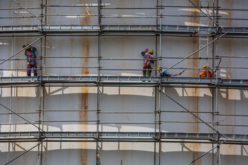 Construction workers tank oil installing scaffolding