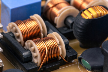 Close up of inductor copper coil on circuit board, copper wire winding soldered on printed, toroidal inductor, selective focus. - obrazy, fototapety, plakaty