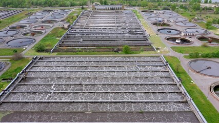 Aerial shot of a wastewater treatment plant and distant skyline. Big city waste processing concept