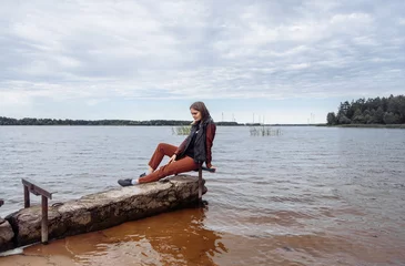 Foto op Canvas young woman near the water river horizon autumn water body of water leather j © Виктория Бычкова