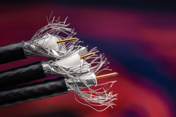 Black coaxial cable is used for TV and satellite installation on blurred color background.