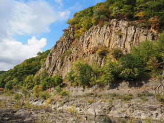切り立った崖に育つ木の紅葉と青空