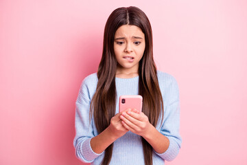 Portrait of attractive worried focused girl using device browsing fake news isolated over pink pastel color background