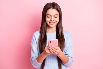 Portrait of attractive cheerful focused girl using device browsing web isolated over pink pastel color background