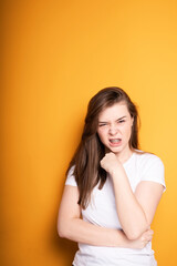 Obraz premium Annoyed girl in a white t-shirt with braces writhes in pain in her teeth clenching her hand into a fist