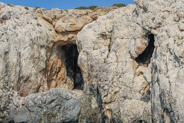 Large cave entrances in a stone cliff above the sea in Cyprus