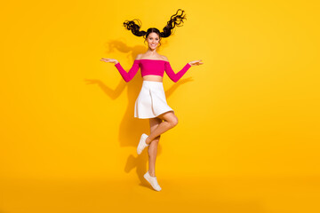 Fototapeta na wymiar Full size photo of optimistic lovely brunette lady jump wear pink top skirt isolated on yellow background