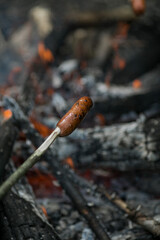 Sausages are fried over a fire.