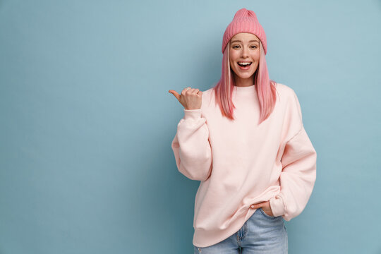 Young Woman Wearing Pink Hat Laughing And Pointing Finger Aside