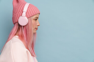 Young white woman wearing pink hat listening music with headphones