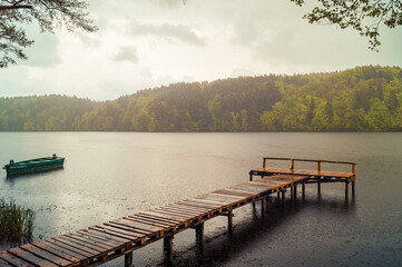 Drewniany pomost nad jeziorem w Łapinie w deszczowy dzień.