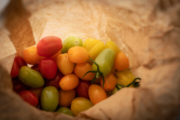 Freshly harvested cherry tomatoes in a paper bag. Locally grown organic tomatoes in different shapes and colors. 
