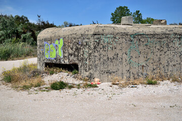 lost teddy bear supported by a World War II concrete bunker on the Black Sea beach - Olimp, Mangalia, Constanta county, Dobrudja, Romania - obrazy, fototapety, plakaty