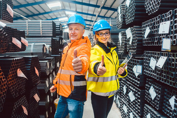 Worker team in warehouse of a steel trade showing thumbs up