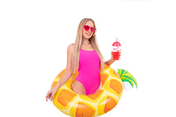 Obraz premium A young woman in a pink swimsuit and glasses holds an inflatable swimming circle and drinks lemonade