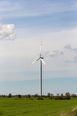 wind turbine in the wind against the backdrop of blue sky with clouds