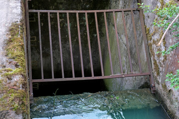 close-up iron rusty grating of a water drain well, a stream flows into a canal, sewage drains, the concept of a drainage system in Europe, a river drainage