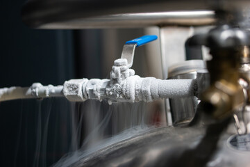 Liquid nitrogen frozen faucet and lever. Visible floating white condensation smoke from pressurized...