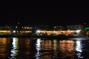 Fototapeta na wymiar Cafe restaurant neighborhood in Syros island Greece at night next to colorful ocean