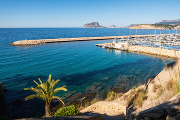 Maritime landscape with a breakwater with a small red lighthouse, in Moraira, Alicante (Spain)