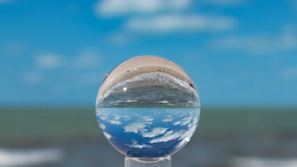 Panoramic ocean view with a bright blue sky, white fluffy clouds and the water reflecting through a crystal ball