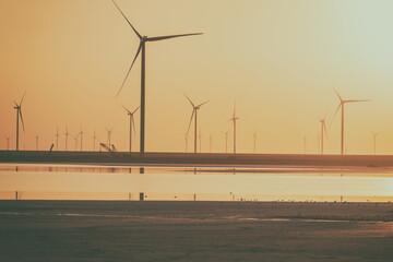Wind farm and the salted lake Syvash at sunset, scenic industrial landscape in yellow tones with...