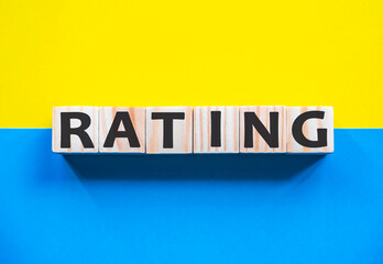 Word RATING on wooden cubes with word on beautiful yellow and blue background. Business, media marketing concept.