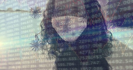 Composition of data processing and covid 19 cells over woman wearing face mask in city