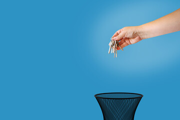A hand is about to throw a bunch of keys into the trash can. Real estate price change concept
