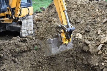 A road excavator dredges the ground foundations near the house
