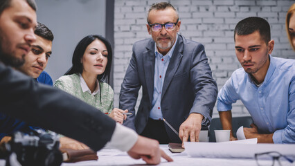Professional group of experienced employees communicating during brainstorming in office analyzing...