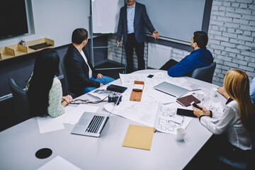 Group of professional experts discussing project and blueprint sketches during conference collaboration in board room, male and female architects have productive briefing in office interior