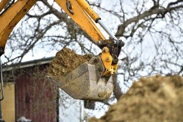 The excavator's shovel picks up the soil while digging on the construction place