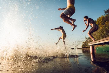 Foto op Canvas Friends having fun enjoying a summer day swimming and jumping at the lake. © Zoran Zeremski