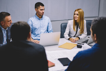 Group of professional colleagues in formal clothing discussing business strategy during exchange briefing, financial experts sitting at office desktop and talking about brainstorming experience