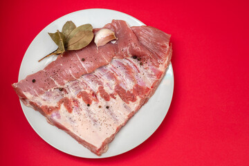 raw ribs with pepper, bay leaf and garlic on white plate