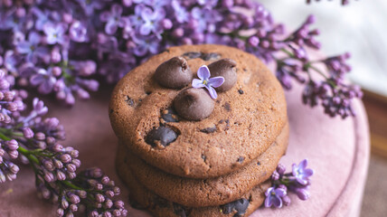 Decorative composition with a Bouquet of lilacs. Clay cup of tea and chocolate cake. A bouquet of lilacs in a vase. Spring floral background with lilacs in the interior. 