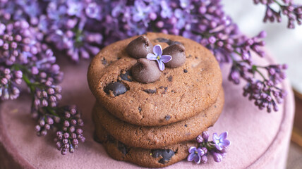 Decorative composition with a Bouquet of lilacs. Clay cup of tea and chocolate cake. A bouquet of lilacs in a vase. Spring floral background with lilacs in the interior. 