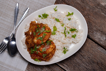 Crispy fried eggs and steamed rice in a white plate on the wooden floor.
