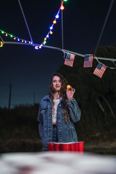 Chica joven jugando al beer pong frente a una caravana por el 4 de julio dia de la independencia de estados unidos