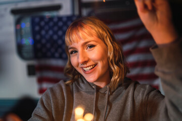 Chica rubia joven con bengalas de chispas frente a caravana con bandera de estados unidos por el dia 4 de julio día de la independencia