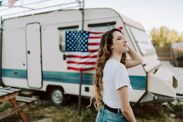 Chica posando y sonriendo frente una caravana con la bandera de estados unidos por el dia 4 de julio